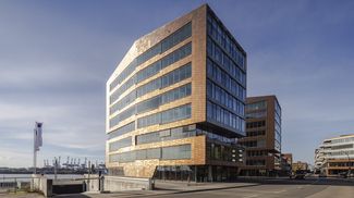 Modernes Bürogebäude in Hamburg mit geschwungener Klinkerfassade, großen Glasflächen und urbanem Umfeld.
